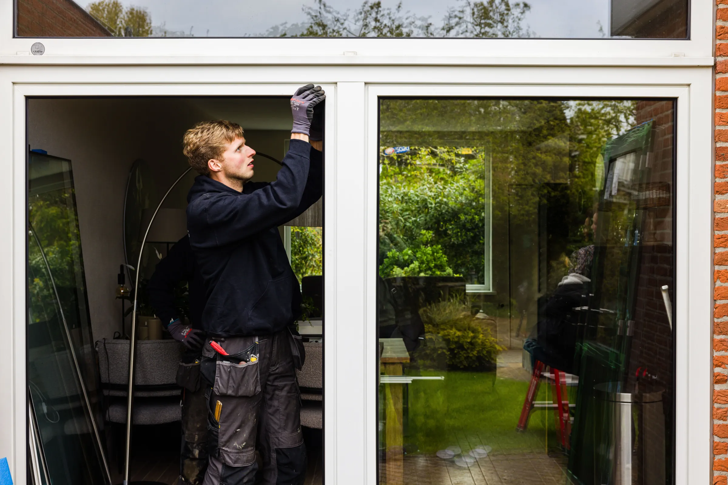 Man plaatst glas in kozijn in woning
